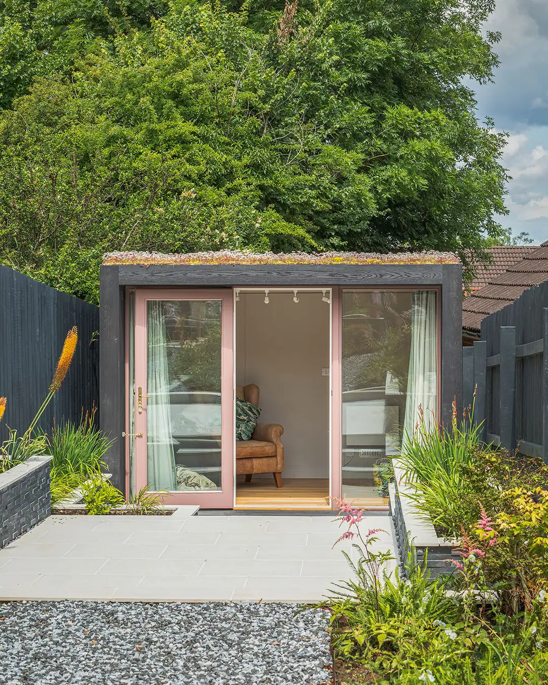 A garden office with pink windows and an open door on a summers day