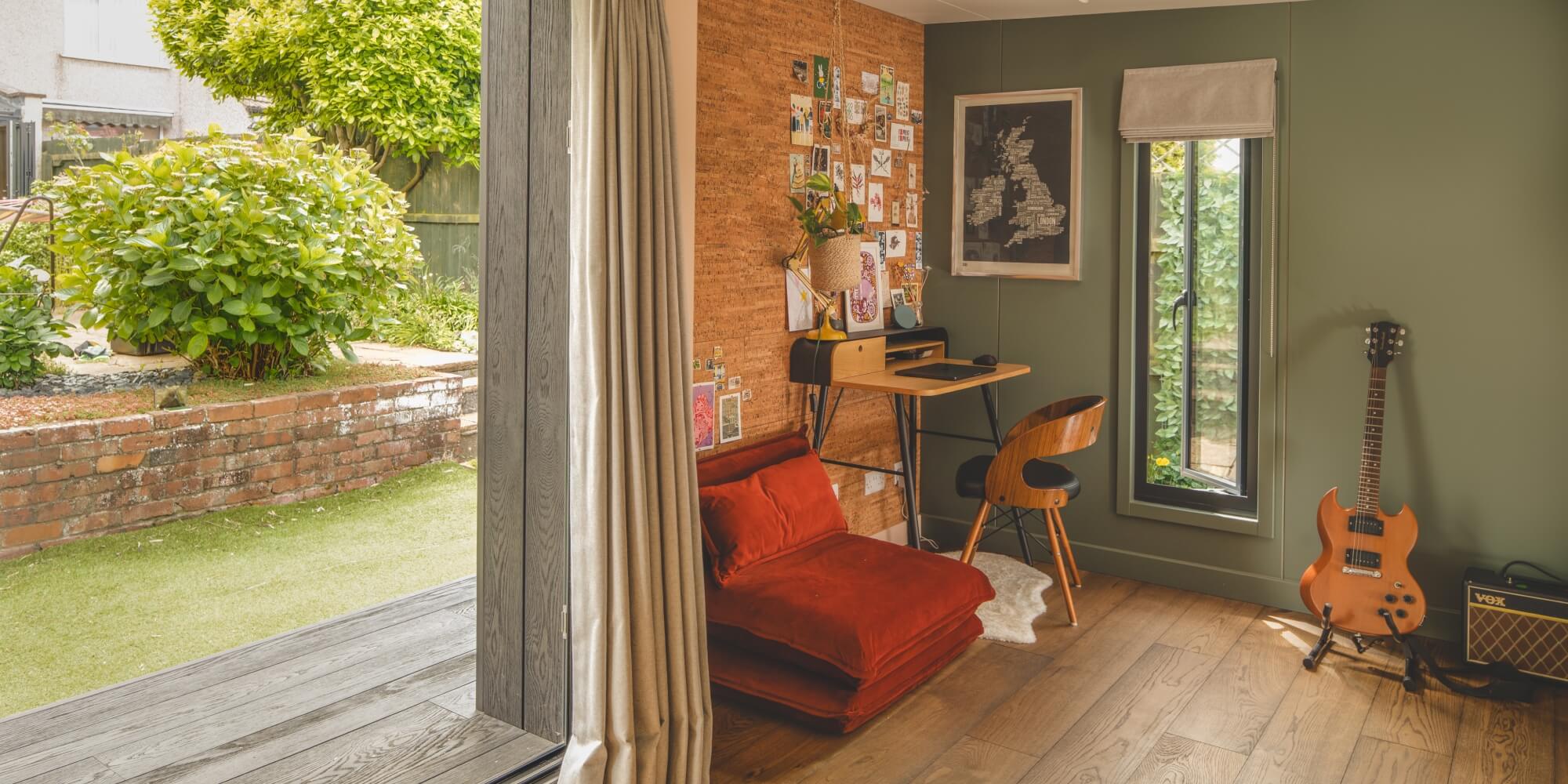 Interior of Little Green Room with guitar and desk, looking out on the garden.