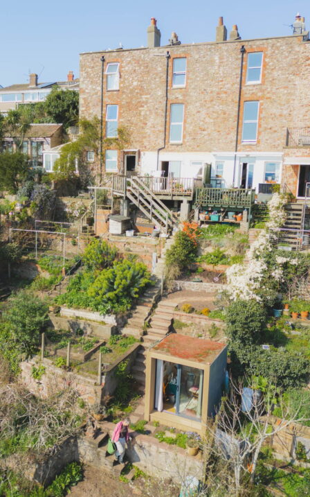 Drone image of Sue's garden. Her walking past her Little Green Room in the garden.