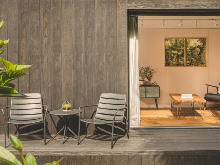 Exterior of Little Green Room in burnt cedar with seating on the decking.