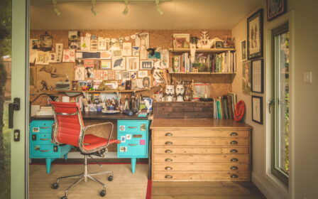 Interior of Little Green Room with desk and art pinned in to the calk wall.