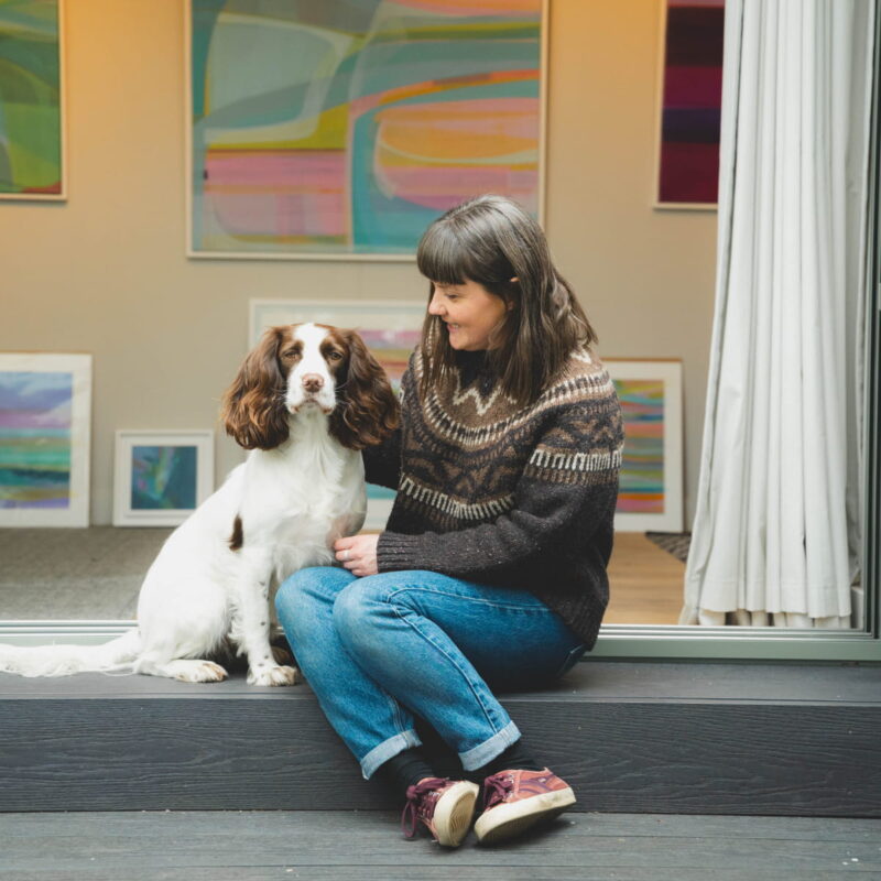 Portrait of Delyth and her spaniel sitting on the decking